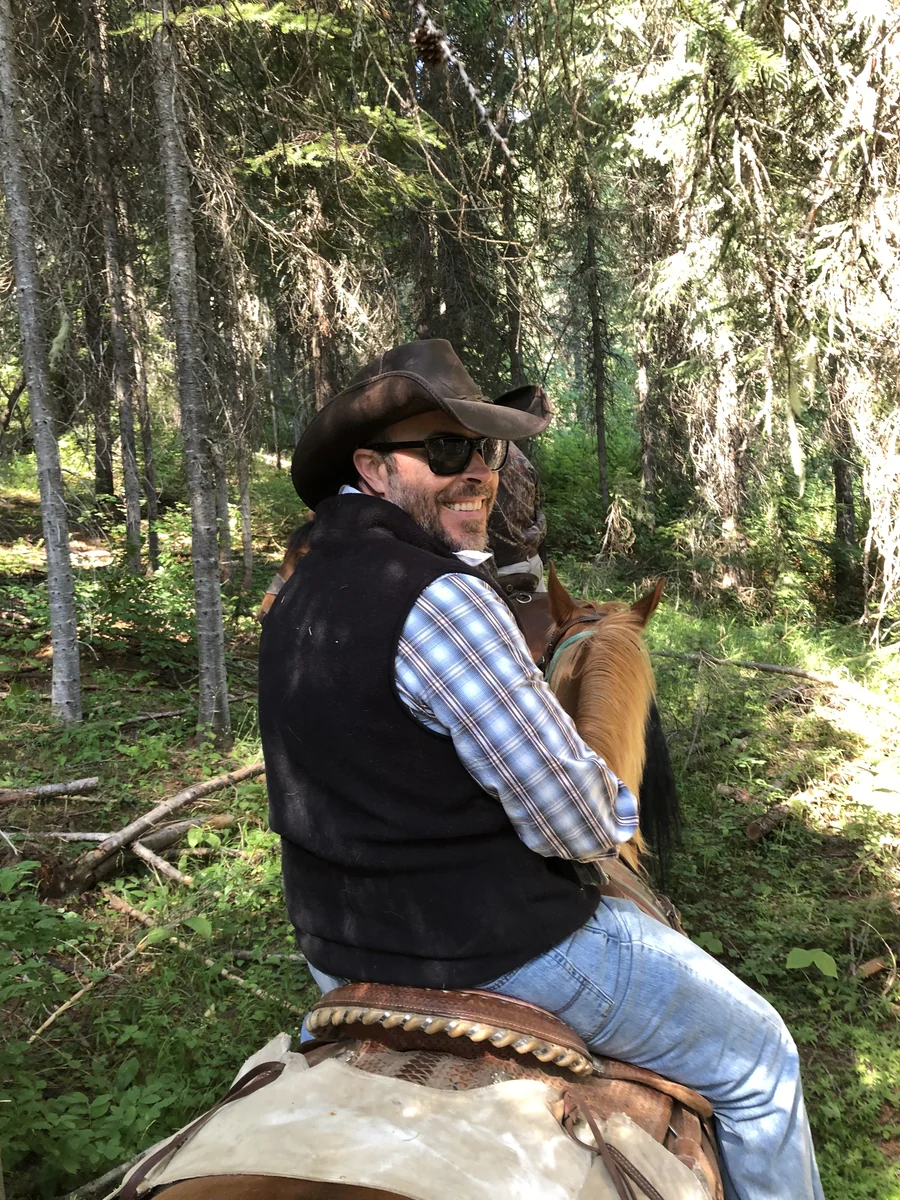 Leslie LeGrand riding a horse on a wooded trail